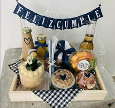 a tray with some food and drinks in it on a table next to a sign that says feliz cumple