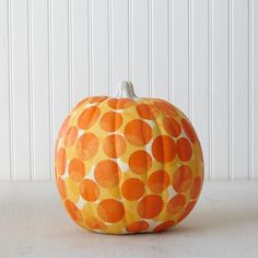 an orange and white pumpkin sitting on top of a wooden table next to a wall