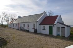 a white house with red roof and green door