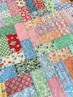 a patchwork quilt with many different colored squares and flowers on the bottom, along with white polka dots