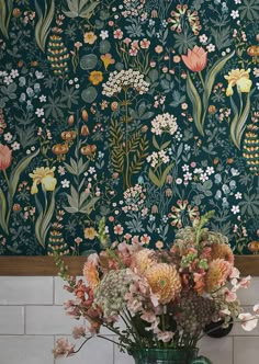 a vase filled with lots of flowers on top of a table next to a wall