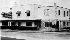 an old black and white photo of a building on the corner of a street with awnings