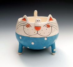 a blue and white cat shaped bowl with polka dots on it's sides, sitting in front of a gray background