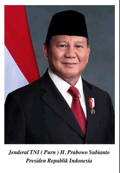 a man in a suit and tie standing next to a flag with words on it