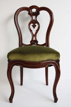 an antique chair with green upholstered seat and wooden frame, against a white background