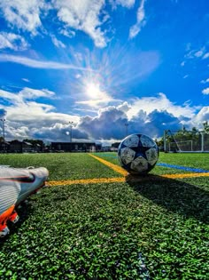 a soccer ball sitting on top of a field next to a goalie's leg