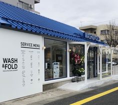 the front of a wash and fold store on a city street with blue roofing