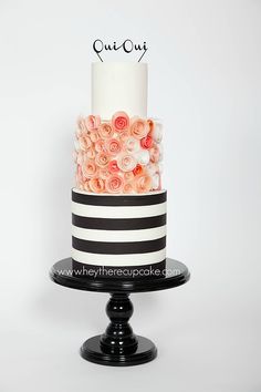 a white and black striped cake with pink roses on the top tier is displayed against a white background