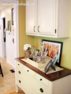 a kitchen with white cabinets and wooden counter tops in front of a refrigerator freezer