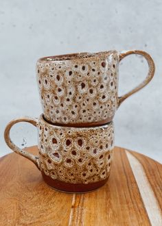 two coffee mugs sitting on top of a wooden table next to each other with holes in them