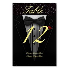 a black and white tuxedo table card with the number twelve in gold on it