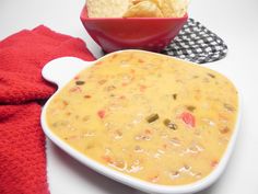 a white bowl filled with cheese and chips next to a red towel