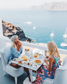 two women sitting at a table with plates of food