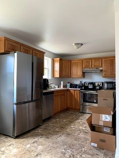 an empty kitchen is shown with boxes stacked on the floor in front of the refrigerator