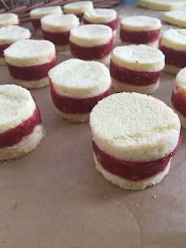 several small cakes sitting on top of a pan covered in frosting and raspberry filling