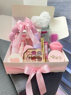 a pink gift box filled with lots of beauty products and personal care items on a chair