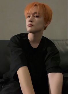 a young man with orange hair sitting on a couch