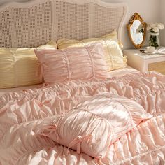 a bed with pink comforter and pillows on it's headboard in a bedroom