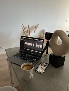 a laptop computer sitting on top of a table next to a cup of coffee