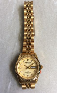 Swanson gold women's watch, having a round sunray gold dial, displaying crystal numbered hours, with day & date indicator at the third hour position, all on a gold linked band. This is a new unused vintage timepiece rated WR5ATM. Measurements: bezel/case 1" in diameter, dial 3/4" in diameter, band width 1/2" and fits a 7" wrist, perfectly. We offer free custom sizing, if a smaller fit is required, just contact us prior to purchasing, for details needed. We ship fast, the next business day, for a quick delivery to you. May you have a wonderful shopping time, best wishes! Displaying Crystals, Vintage Timepiece, Best Wishes, Women Wrist Watch, Women's Watch, Fort Lauderdale, Gold Band, Quick Delivery, Gold Bands