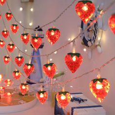 many red hearts are hanging from strings in the room with other decorations on the wall