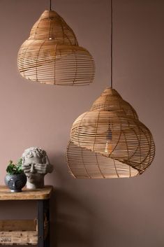 three hanging lights made out of bamboo on a table next to a vase and plant