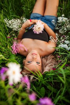 a woman laying in the grass with flowers