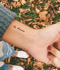 two people holding hands with the word love tattooed on them