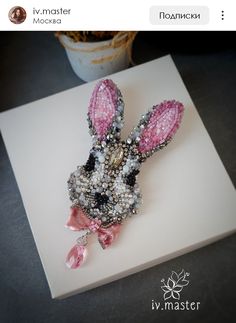 a pink and black bunny brooch sitting on top of a white card with the words i'm master written in russian