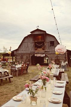 an old barn with tables and chairs set up for a rustic wedding reception in front of it