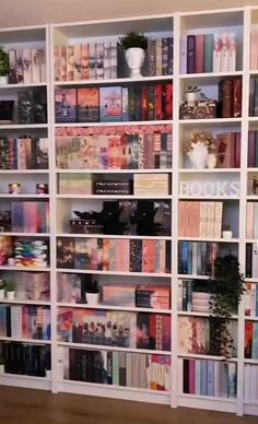 a book shelf filled with lots of books on top of wooden flooring next to a white wall