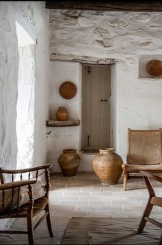 a room with two chairs and some vases on the wall next to each other