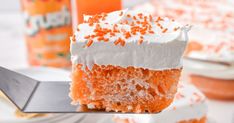 a piece of cake with white frosting and orange sprinkles on it