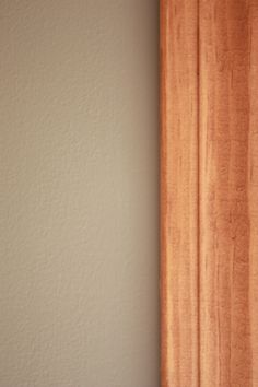 a cat sitting on the edge of a window sill in front of a curtain