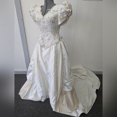 a white wedding dress on display in front of a wall