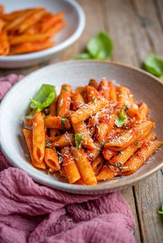 a bowl filled with pasta and sauce on top of a wooden table