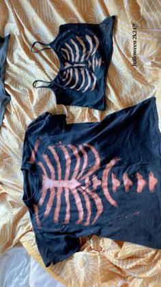 two pieces of clothing are laying on a bed with an orange and black design painted on them