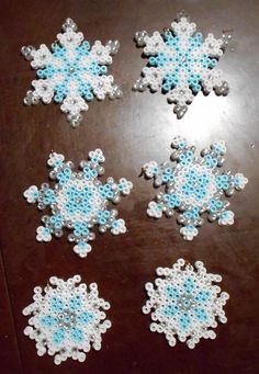 four snowflakes are arranged on a wooden table, one is blue and the other is white