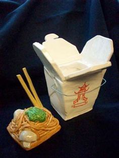 two small containers with chopsticks in them next to each other on a black surface