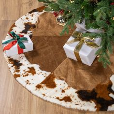 a cowhide rug with presents on it and a christmas tree in the corner next to it