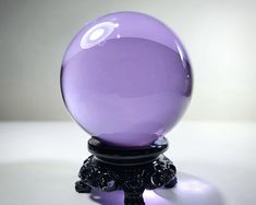 a purple glass ball sitting on top of a black stand