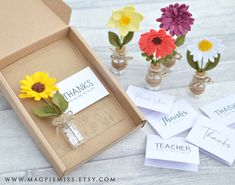 small vases filled with flowers sitting on top of a wooden table next to thank note cards