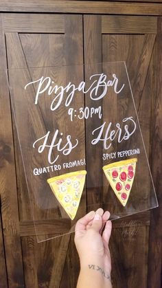 a person holding two slices of pizza in front of a wooden door with writing on it