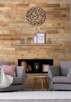 a living room with two gray couches and a clock on the wall above it