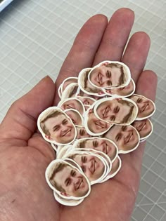 a hand holding a bunch of stickers with a man's face on them