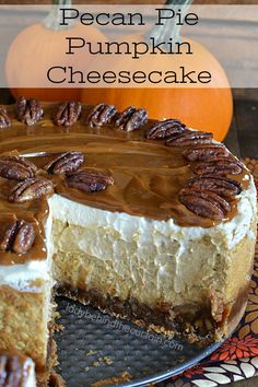 a cheesecake with pecans and caramel is on a plate next to two pumpkins