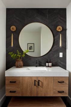 a bathroom vanity with a round mirror above it and two wooden drawers underneath the sink