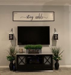 a flat screen tv mounted to the side of a wall next to potted plants