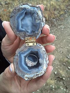 a person holding two pieces of jewelry in their hands, one with a ring on it