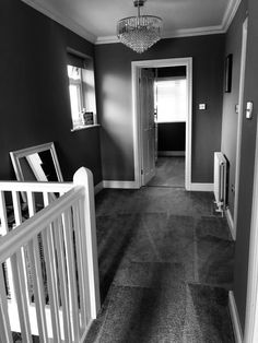 an empty hallway with a chandelier hanging from the ceiling and carpet on the floor